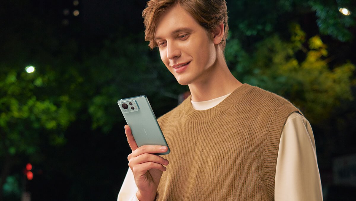 Een lachende man die naar zijn Asus Zenfone 12 Ultra (Green Sage) kijkt