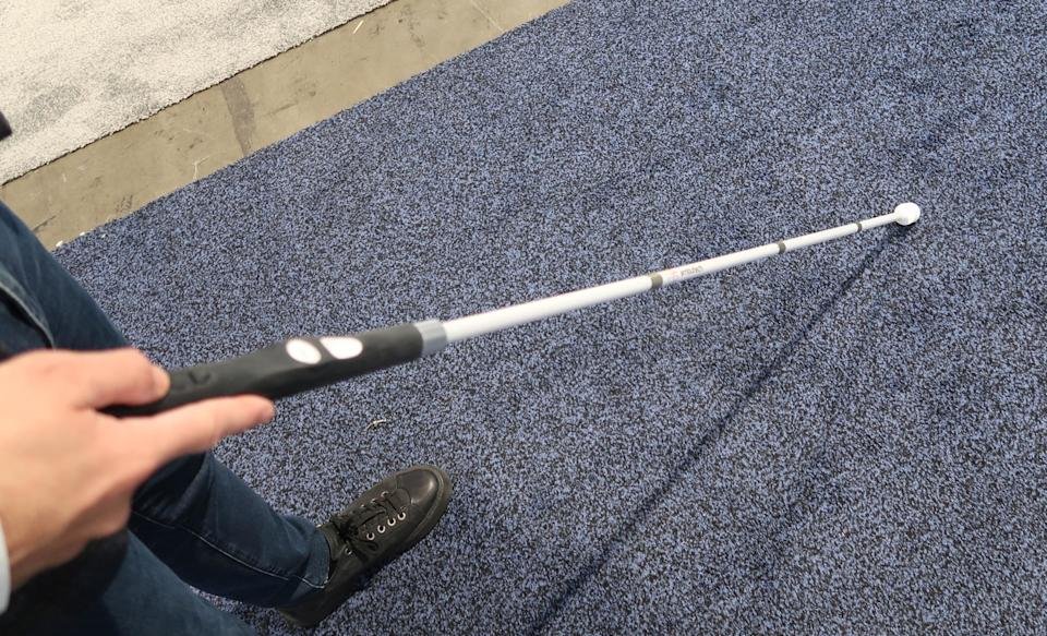 Iemand gebruikt Wewalk Smart Cane 2 om zijn weg te vinden op een CES-stand.