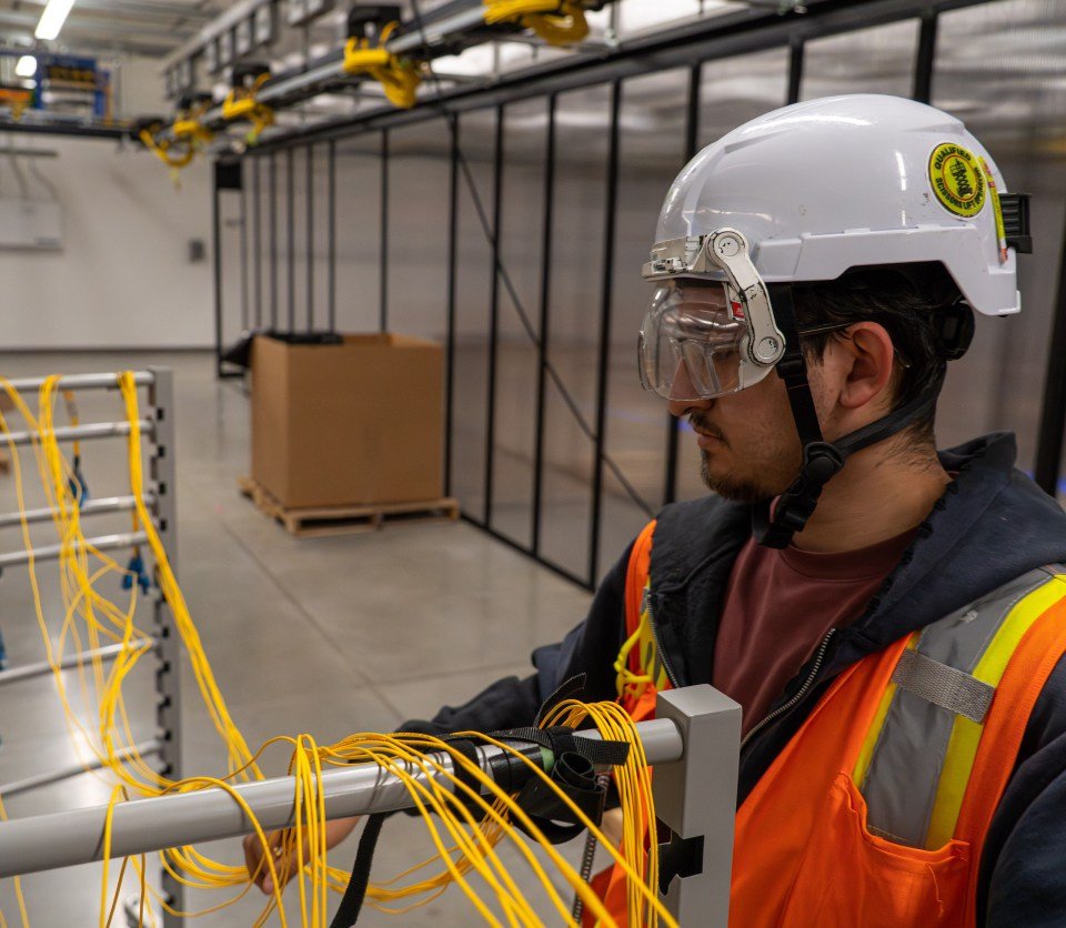 Afbeelding van een glasvezeltechnicus die in een datacenter werkt.