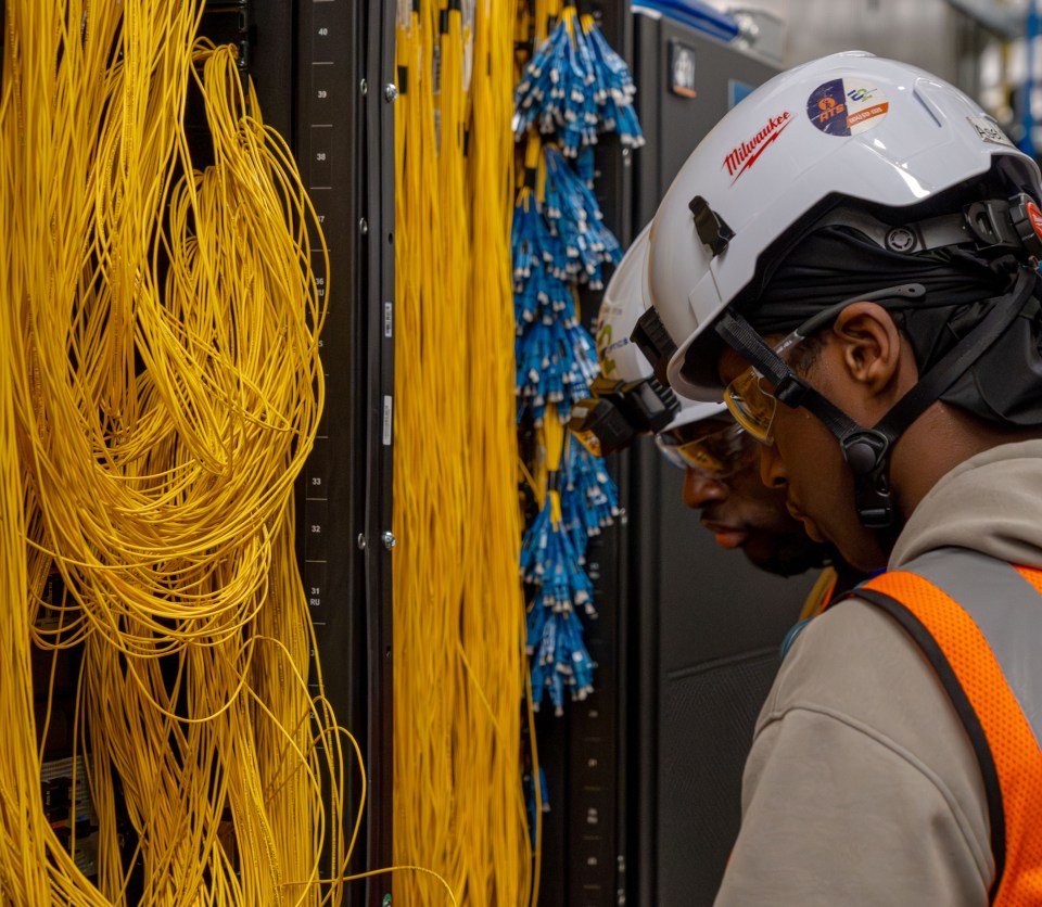 Afbeelding van een glasvezeltechnicus die in een datacenter werkt.